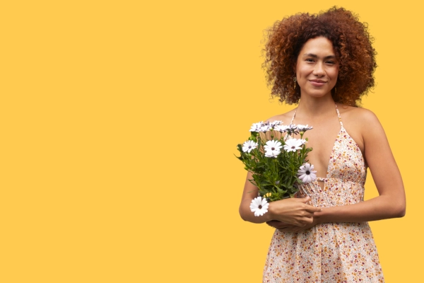 black female model in floral dress holding daisies