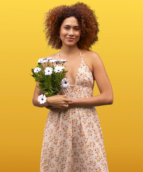 Black female model wearing a sexy ditsy pattern dress holding white daisies